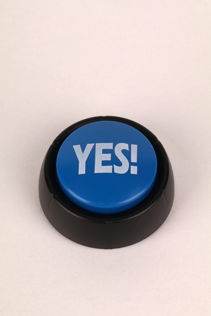 Close-up of a blue button with 'Yes!' text on a beige background, perfect for communication themes.